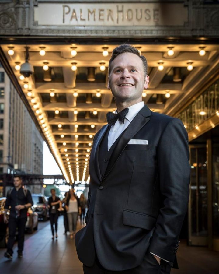 Dennis Watkins standing in front of the historic Palmer House hotel smiling. 